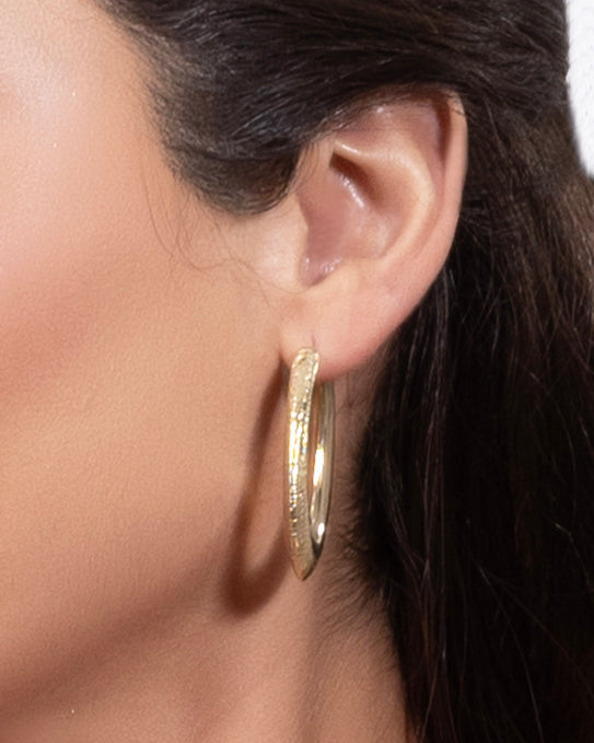Close-up of sculpted gold textured hoop earrings